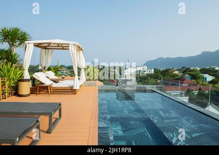 Chaises longues au bord de la piscine à débordement, piscine à débordement luxueuse le matin Banque D'Images