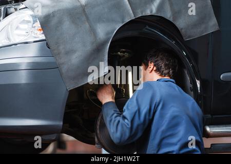 Un mécanicien inspecte le système de suspension de la voiture Banque D'Images