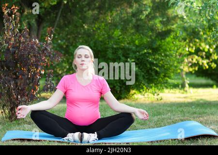 Jolie femme enceinte pratiquant le yoga en plein air Banque D'Images
