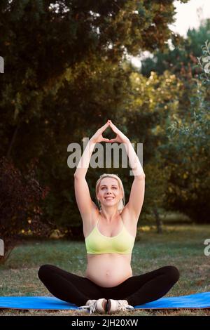 Grossesse souriante pratiquant le yoga dans la nature Banque D'Images