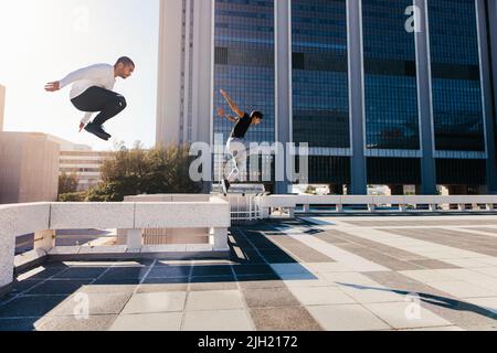 Deux jeunes sportifs pratiquant le parkour sur fond de ville. Jeunes pratiquant des activités sportives extrêmes en plein air en ville. Les athlètes masculins courent Banque D'Images