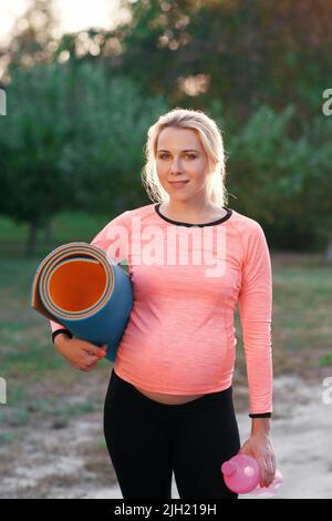 Femme de fitness enceinte souriant à l'appareil photo Banque D'Images