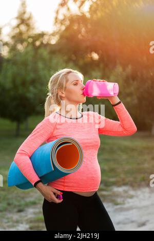 Femme enceinte qui boit de l'eau après la remise en forme Banque D'Images