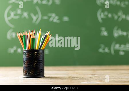 Image d'une tasse avec crayons au-dessus de formules mathématiques sur tableau noir Banque D'Images