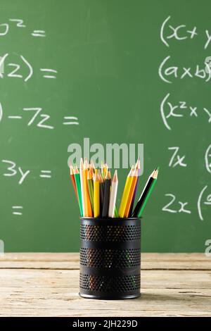 Image d'une tasse avec crayons au-dessus de formules mathématiques sur tableau noir Banque D'Images