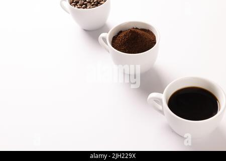 Image de trois tasses de café moulu, de grains de café et de café sur fond blanc Banque D'Images