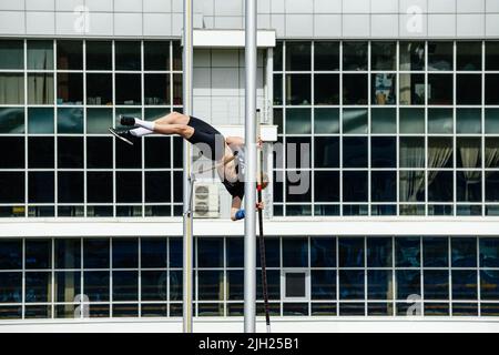 saut à la perche d'athlète masculin sur fond de bâtiment Banque D'Images