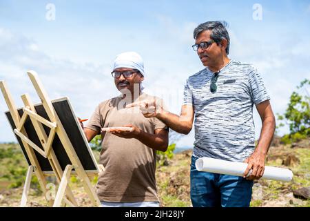 Les artistes d'âge moyen s'affairés à peindre au sommet de la colline en discutant devant la tente de camping - concept de liberté créative, activités de loisirs et Banque D'Images