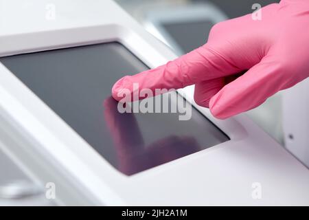 Le médecin-cosmétologue règle l'appareil pour le photoréjuvenation à l'aide de l'écran tactile Banque D'Images