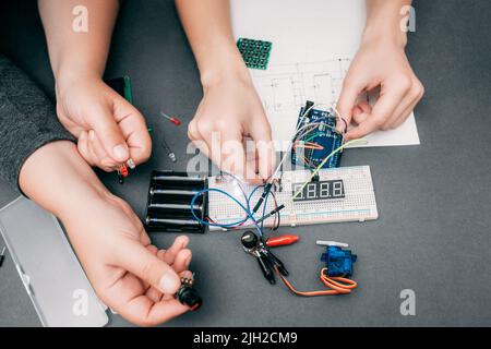 Les ingénieurs connectent les composants électroniques à leurs mains Banque D'Images