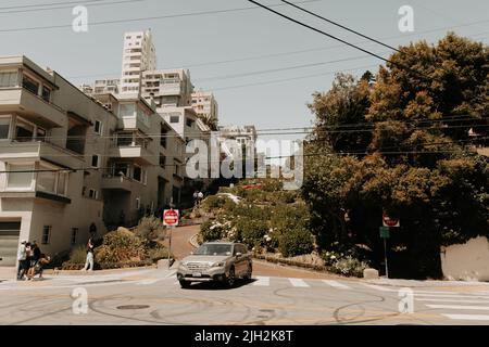 Les voitures qui descendent les huit tours en épingle à cheveux sur la célèbre Lombard Street dans la ville de San Francisco. Les touristes se tenant sur le côté de prendre des photos de voitures. Banque D'Images