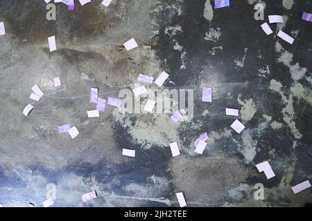 Fond en béton festif avec confettis holographiques. Beige, gris, bleu et violet sur le béton. Un arrière-plan avec beaucoup de particules de violet carré et de blanc. Photo de haute qualité Banque D'Images