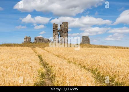 Les marques de roue de tracteur mènent à l'église en ruines de St James, vue en juillet 2022 à Bawsey, dans l'ouest du Norfolk. Banque D'Images