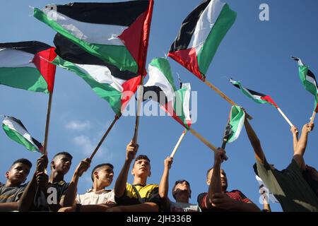 Gaza, Palestine. 14th juillet 2022. Les manifestants palestiniens scandent des slogans et brandent le drapeau national alors qu'ils se rassemblent pour protester contre la visite du président américain Joe Biden en Israël à Gaza jeudi, 14 juillet 2022. Crédit : UPI/Alay Live News Banque D'Images