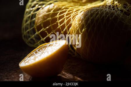 Citrons dans la grille vue rapprochée. Fruit dans les rayons du soleil sur fond sombre. Citron tranché. Banque D'Images