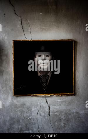 Une peinture d'un homme masqué est suspendue sur un mur brisé Banque D'Images