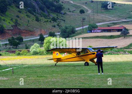 Petit avion jaune d'hélice sur l'herbe à un jour ensoleillé et les gens autour de l'avion Banque D'Images