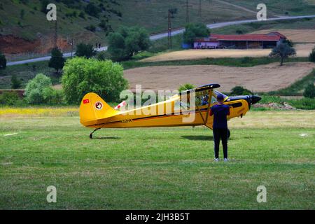 Petit avion jaune d'hélice sur l'herbe à un jour ensoleillé et les gens autour de l'avion Banque D'Images