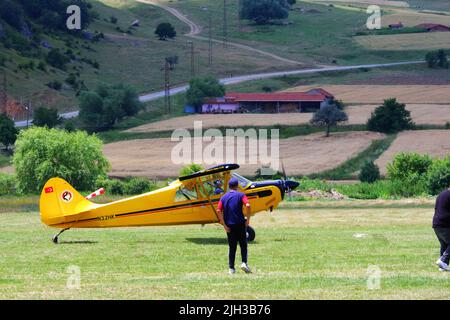 Petit avion jaune d'hélice sur l'herbe à un jour ensoleillé et les gens autour de l'avion Banque D'Images