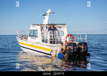 Des Dénés, en bateau, recueillent de l'eau potable fraîche du Grand lac Bear, à l'extérieur de la communauté autochtone de Deline, Territoires du Nord-Ouest, Canada. Banque D'Images