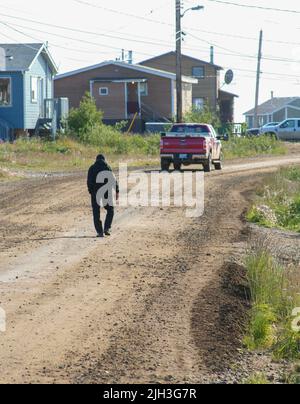 Un homme âgé marchant le long de la route de terre de la communauté indigène du nord de Deline en été, Territoires du Nord-Ouest, Canada. Banque D'Images