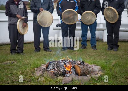 Hommes autochtones tenant des tambours dénés traditionnels lors de la cérémonie d'alimentation au feu, dans la communauté nord de Deline, Territoires du Nord-Ouest, Canada Banque D'Images