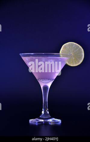 Cocktail cosmopolite, boisson rafraîchissante dans un grand verre avec glace et une tranche de citron sur fond noir. Positionnement vertical. Banque D'Images