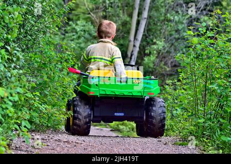 Vue arrière d'un jeune garçon conduisant son 4x4 jouet sur un sentier de parc dans les régions rurales de l'Alberta au Canada Banque D'Images