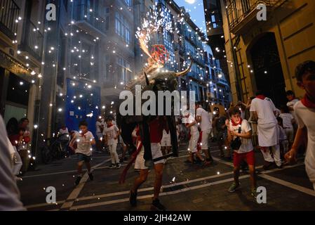 Pampelune, Espagne. 14th juillet 2022. Les enfants courent devant le taureau de feu pendant les festivités de San Fermín. Un homme portant une structure en forme de taureau chargée de feux d'artifice appelé Toro de Fuego (taureau de feu), tire le feu et court dans les rues de la vieille ville de Pampelune pendant les festivités de San Fermín. Crédit : SOPA Images Limited/Alamy Live News Banque D'Images