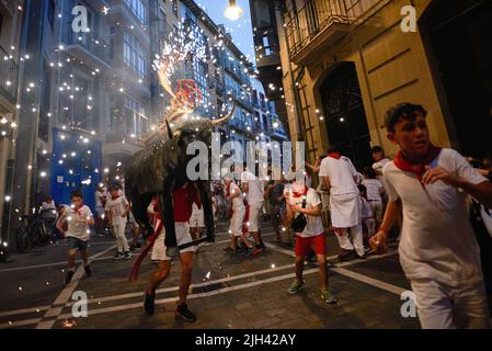 Pampelune, Espagne. 14th juillet 2022. Les enfants courent devant le taureau de feu pendant les festivités de San Fermín. Un homme portant une structure en forme de taureau chargée de feux d'artifice appelé Toro de Fuego (taureau de feu), tire le feu et court dans les rues de la vieille ville de Pampelune pendant les festivités de San Fermín. Crédit : SOPA Images Limited/Alamy Live News Banque D'Images