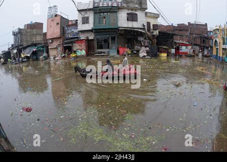 Lahore, Punjab, Pakistan. 14th juillet 2022. Les ouvriers pakistanais transportent des sacs d'oignons et de pommes de terre et se wade à travers une route inondée au marché aux légumes de Badami Bagh après une forte pluie de mousson dans la capitale provinciale Lahore. (Credit image: © Rana Sajid Hussain/Pacific Press via ZUMA Press Wire) Banque D'Images