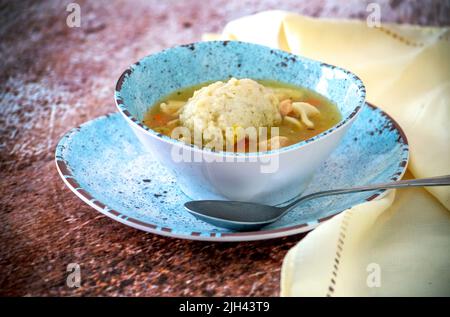 Bol chaud de soupe de nouilles de poulet, avec une grosse boule de mazzo moelleuse flottant sur le dessus Banque D'Images