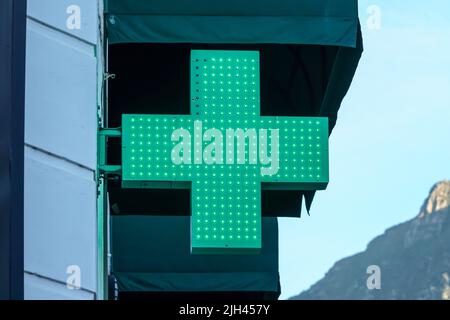 Une croix verte illuminée ou allumée indique que la pharmacie, le pharmacien, le dispensaire, le magasin de médicaments, un symbole international, affiche ou affiche en gros plan Banque D'Images