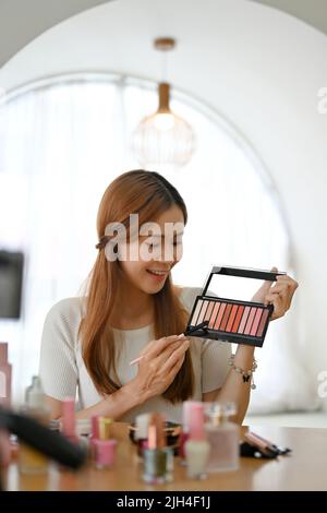 Attrayante et charmante jeune asiatique femme beauté blogger ou maquilleur faisant son maquillage, donnant un maquillage conseils pour son blog de beauté, montrant son oeil Banque D'Images