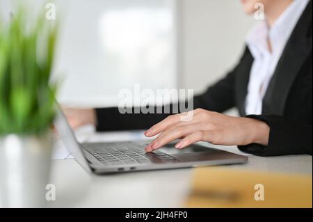 En gros plan, Une femme d'affaires concentrée en costume habillé se trouve à son bureau, à l'aide d'un ordinateur portable, en tapant sur le clavier, en travaillant sur ses affaires Banque D'Images