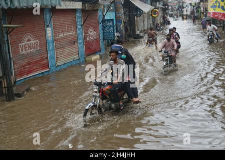 Lahore, Pakistan. 14th juillet 2022. Les ouvriers pakistanais transportent des sacs d'oignons et de pommes de terre et se wade à travers une route inondée au marché aux légumes de Badami Bagh après une forte pluie de mousson dans la capitale provinciale Lahore. (Photo de Rana Sajid Hussain/Pacific Press/Sipa USA) crédit: SIPA USA/Alay Live News Banque D'Images