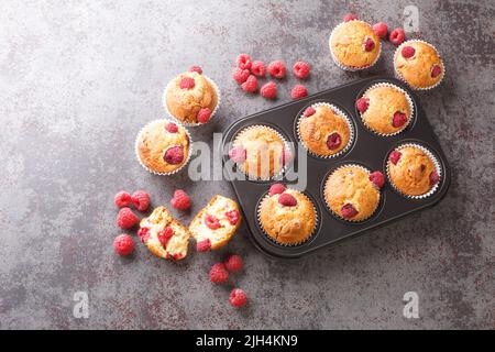 Muffins fraîchement cuits avec framboises et chocolat blanc dans un moule à muffins sur la table. Vue horizontale du dessus Banque D'Images