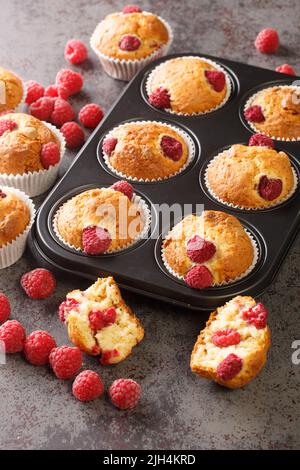 Muffins d'été aux framboises au chocolat blanc en gros plan dans un moule à muffins sur la table. Verticale Banque D'Images