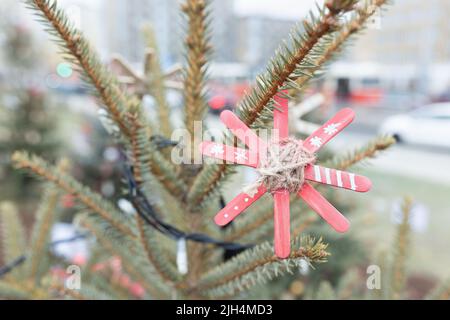 Décoration faite à la main sur l'arbre de Noël extérieur fait de bâtons de glace artisanal en bois peint en rouge. Idées de bricolage pour les enfants. Environnement, recyclage et zéro déchet concept. Mise au point sélective Banque D'Images