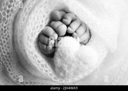 Le pied minuscule d'un nouveau-né. Pieds doux d'un nouveau-né dans une couverture de laine. Coeur tricoté dans les jambes de bébé. Banque D'Images