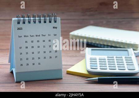 Avril 2023 calendrier de bureau blanc sur table en bois avec bloc-notes, calculatrice et arrière-plan de stylo. Concept de la nouvelle année et espace de copie Banque D'Images