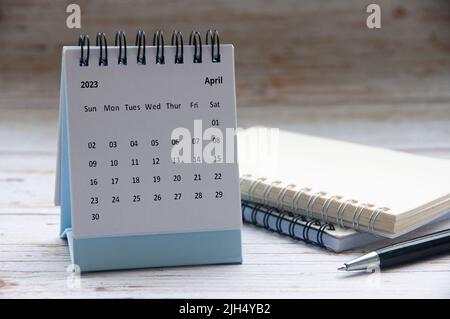 Avril 2023 calendrier blanc de bureau sur table en bois avec bloc-notes et arrière-plan de stylo. Concept de la nouvelle année et espace de copie Banque D'Images