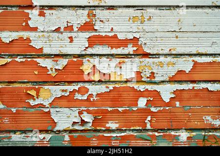 Des couches de peinture crème, orange et verte se détachent d'une surface métallique Banque D'Images