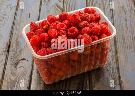 Plateaux avec framboises sur fond en bois. Banque D'Images