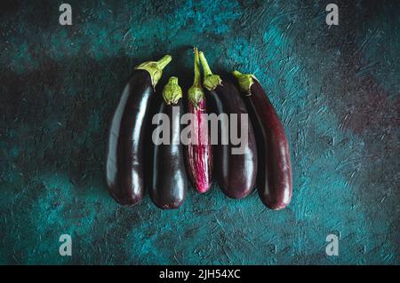 Aubergines fraîches, pourpres et rayées, différentes couleurs et variétés sur fond sombre Banque D'Images