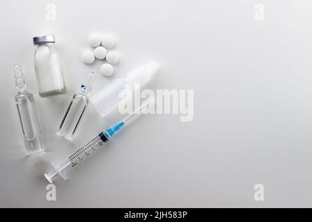 Tout pour le traitement sur fond blanc : comprimés blancs ronds, médicaments en ampoules, solution injectable, gouttes nasales, seringue jetable Banque D'Images