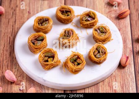 Bulbul Kadayif avec Pistachio. Kadayif baklava avec remplissage de pistache sur un plancher en bois. Desserts de cuisine turque. Gros plan. Nom local Antep Fıstıklı Banque D'Images