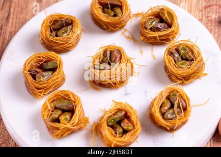 Bulbul Kadayif avec Pistachio. Kadayif baklava avec remplissage de pistache sur un plancher en bois. Desserts de cuisine turque. Gros plan. Nom local Antep Fıstıklı Banque D'Images