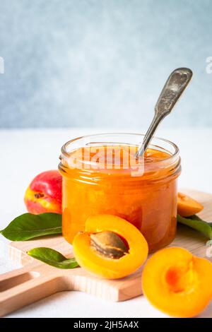 Confiture d'abricot dans un pot en verre à la table blanche. Banque D'Images