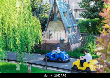 Russie, Sotchi 14.05.2022. Un père dans une voiture jaune pour enfants suit son fils dans une voiture bleue. Animations pour les enfants et les adultes. Circuit enfants i Banque D'Images